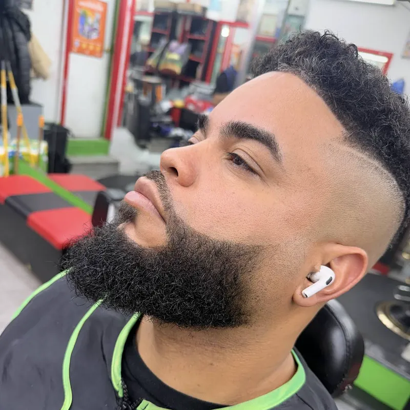 Razor cut: high fade with a razor-cut part, curly top and full beard