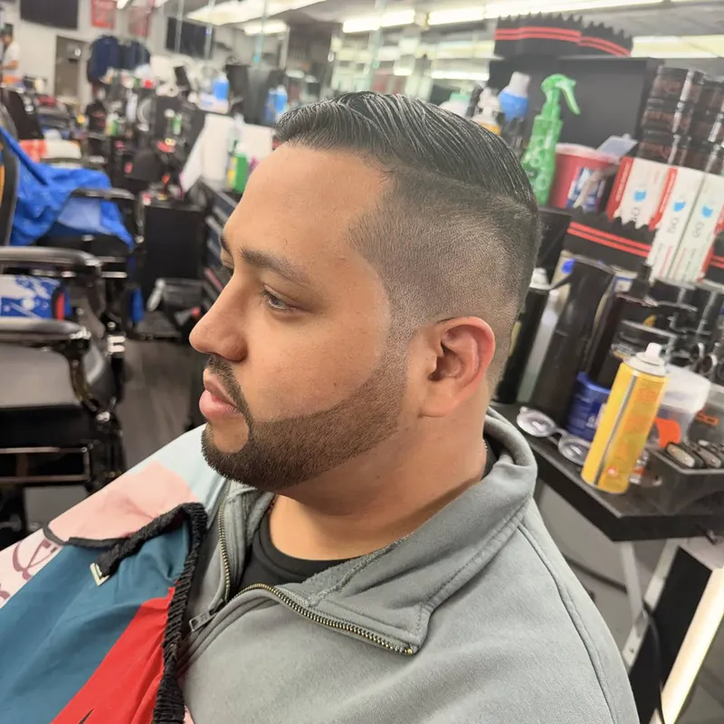 Slicked-back top with a mid fade and short boxed beard